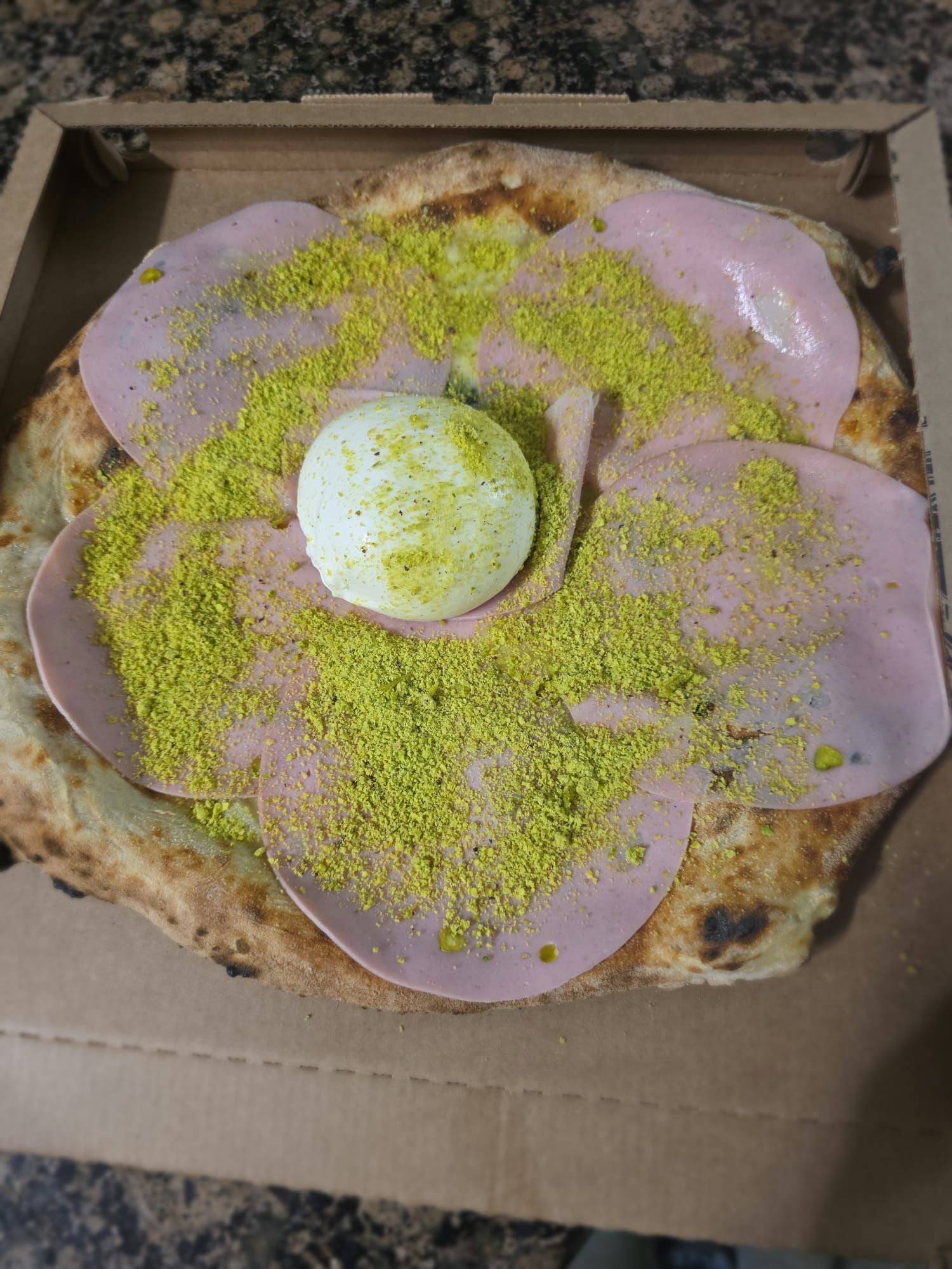 Pizza con mortadella, granella di pistacchio e burrata al centro, nel cartone da asporto