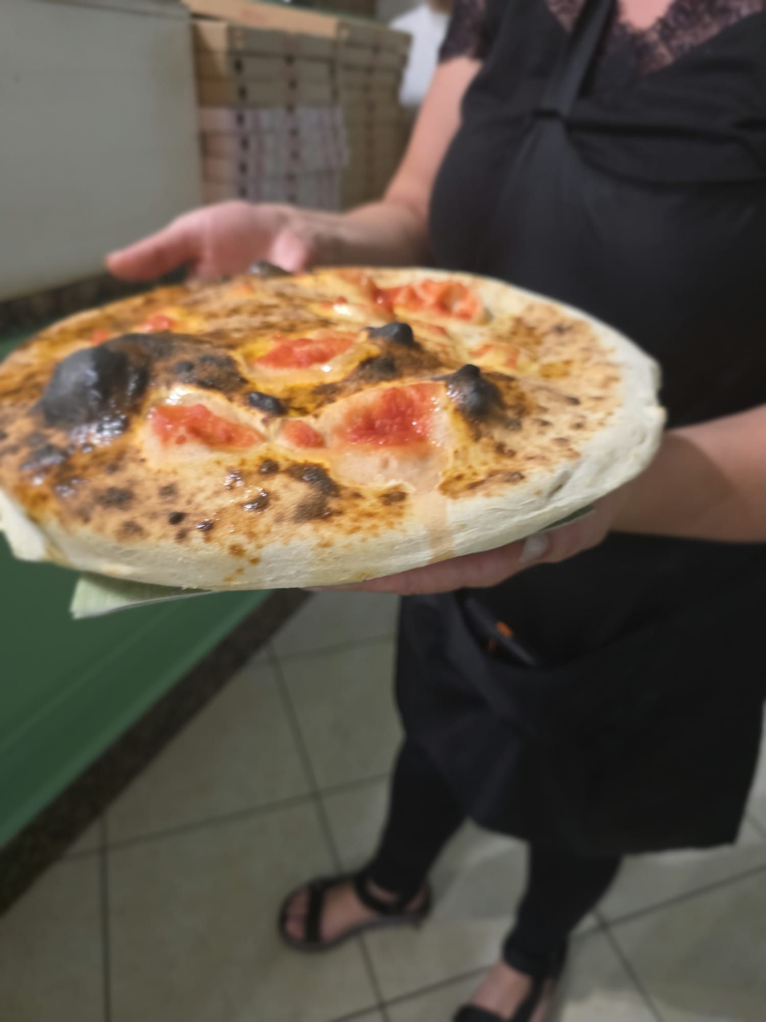 Una pizza appena uscita dal forno portata al tavolo